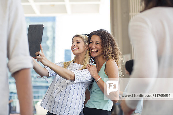 Zwei glückliche Frauen nehmen einen Selfie mit Tablette auf dem Stadtplatz.