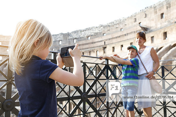 Italy  Rome  little girl taking picture of mother and brother with smartphone