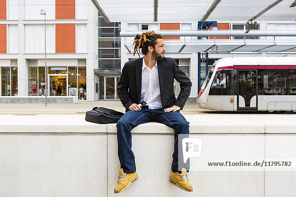 Young businessman with dreadlocks waiting at station