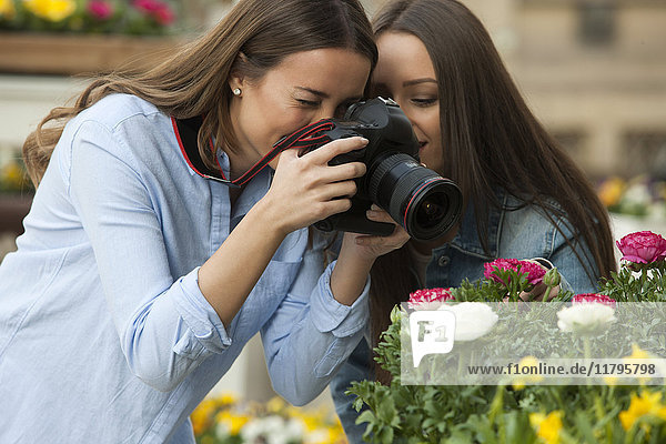 Girlfriends photographing potted plants at flower stall