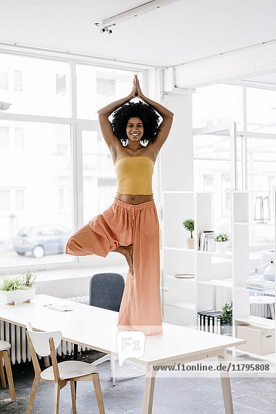 Junge Frau beim Yoga auf dem Schreibtisch