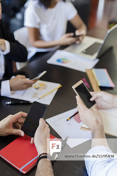 Geschäftsleute  die Mobiltelefone während eines Meetings im Büro benutzen