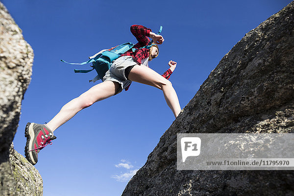 Spanien,  Madrid,  junge Frau,  die während eines Trekkingtages zwischen Felsen springt.