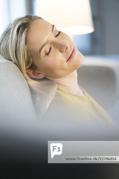 Portrait of blond woman with eyes closed relaxing on couch