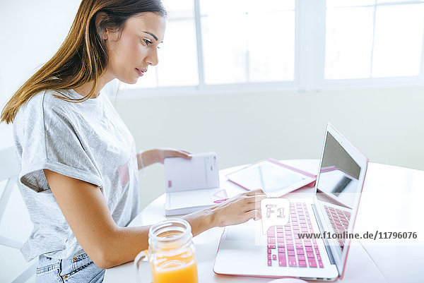 Young woman working at home with laptop and tablet