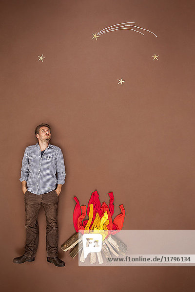 Junger Mann am Lagerfeuer mit Blick auf die Sterne