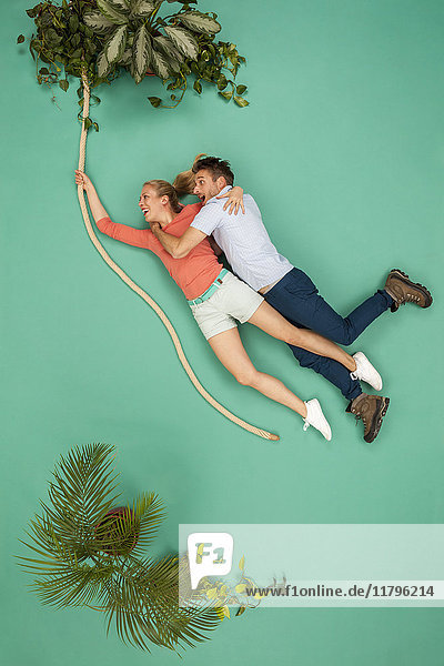 Couple swinging on a liana through the jungle