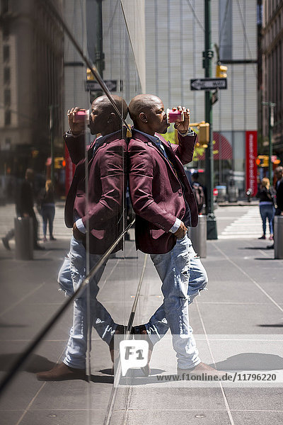USA  New York City  Manhattan  stilvoller Geschäftsmann mit Kaffee zum Anlehnen an Glasfassade