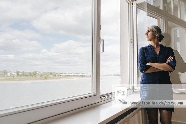 Geschäftsfrau mit Blick aus dem Fenster im Büro am Wasser