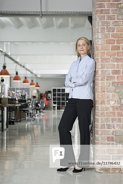 Mature businesswoman leaning against brick wall