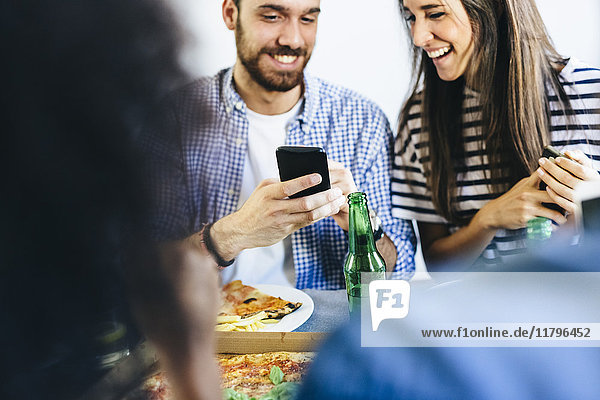 Happy couple sharing cell phone at dining table