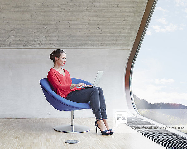 Frau sitzend auf Stuhl im Dachgeschoss Büro mit Laptop