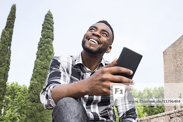 Porträt eines glücklichen jungen Mannes mit Handy