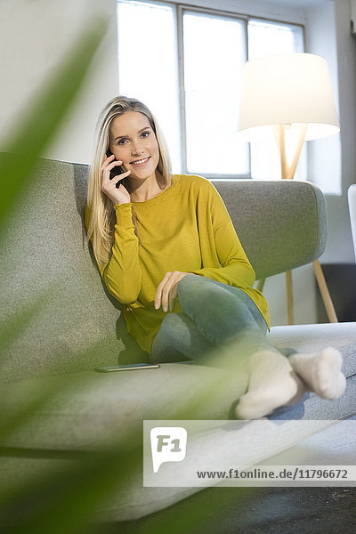 Porträt einer lächelnden jungen Frau am Telefon zu Hause
