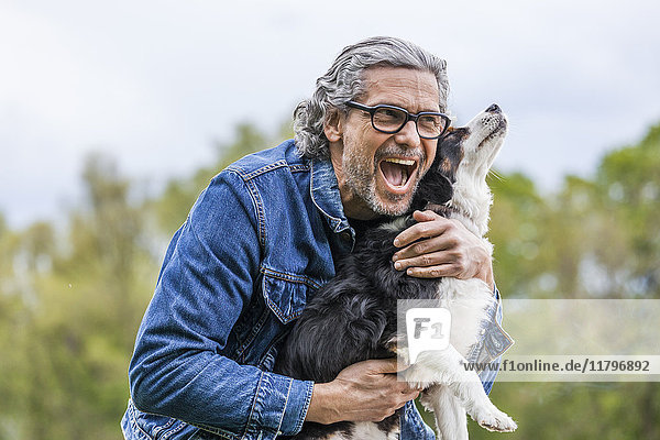 Portrait of happy senior man cuddling his dog