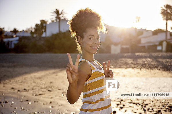 Portrait of woman showing victory sign on the beach