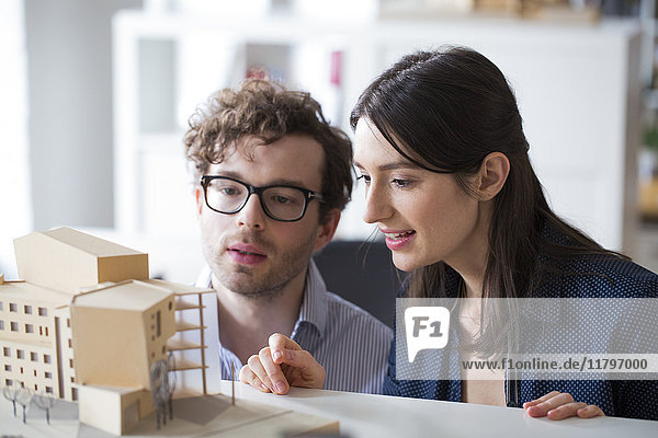 Man and woman discussing architectural model in office