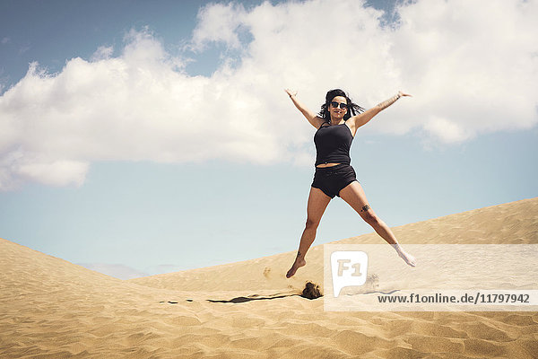 Woman jumping on sand dune
