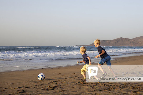 Boys playing soccer on beach