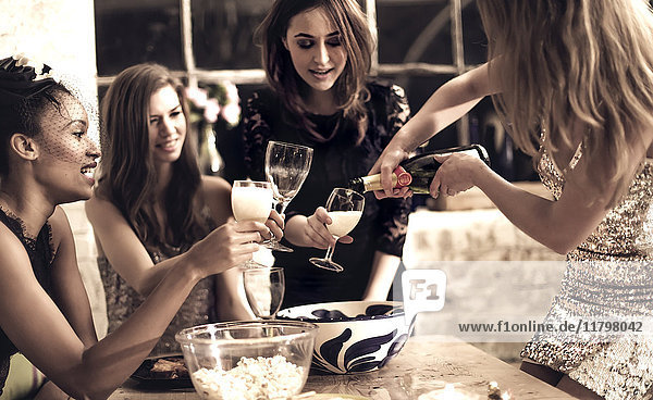 A group of women at a party  pouring and drinking champagne.