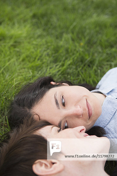 Ein gleichgeschlechtliches Paar  zwei Frauen  die im Gras liegen  sich zärtlich anschauen und sich entspannen.