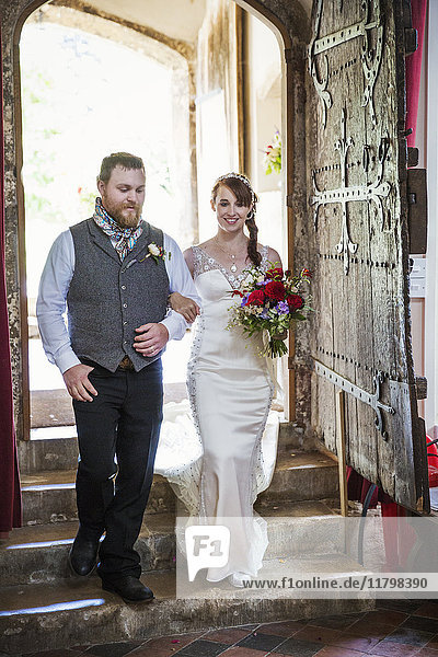 Lächelnde Braut und Bräutigam beim Betreten der Kirche.