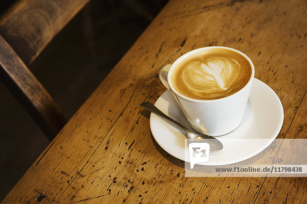 Nahaufnahme aus hohem Winkel einer Tasse Cappuccino auf einem rustikalen Holztisch  Herzform in Milchschaum.