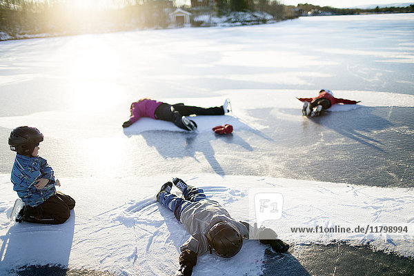 Mutter mit Kindern macht Schneeengel auf dem zugefrorenen See