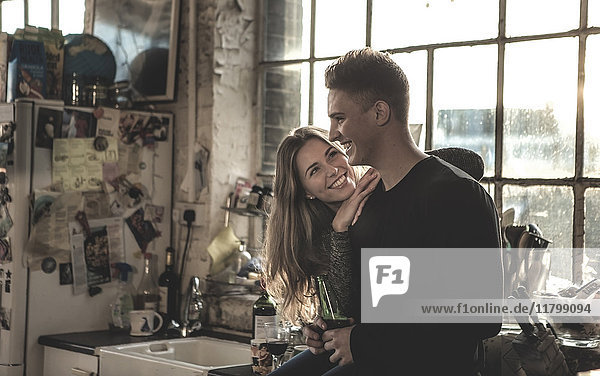 Smiling young woman and young man standing indoors by a window.