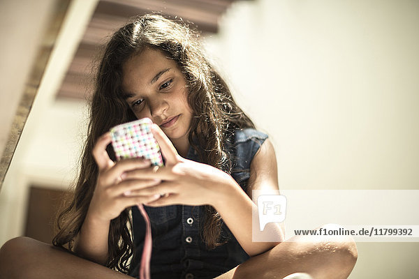 Niedrigwinkelaufnahme eines Mädchens  das auf den Bildschirm eines Mobiltelefons schaut.
