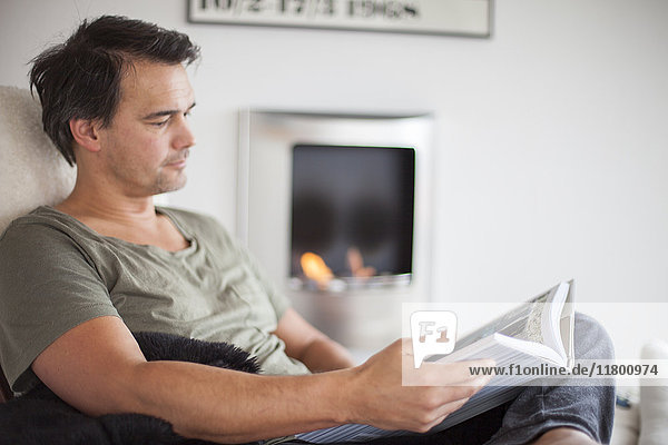 Mann liest Buch zu Hause