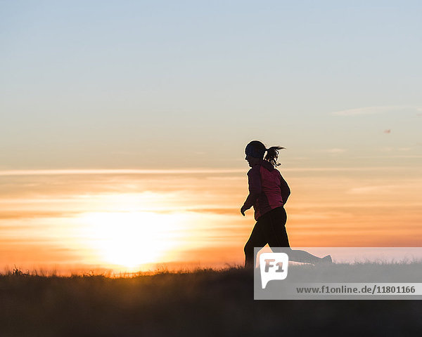 Frau läuft bei Sonnenuntergang