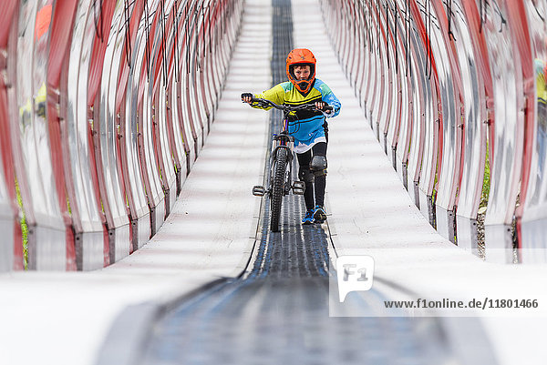 Junge geht mit Fahrrad durch einen Tunnel