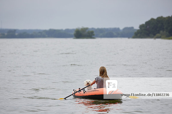 Junge Frau mit Hund schwimmt im Schlauchboot