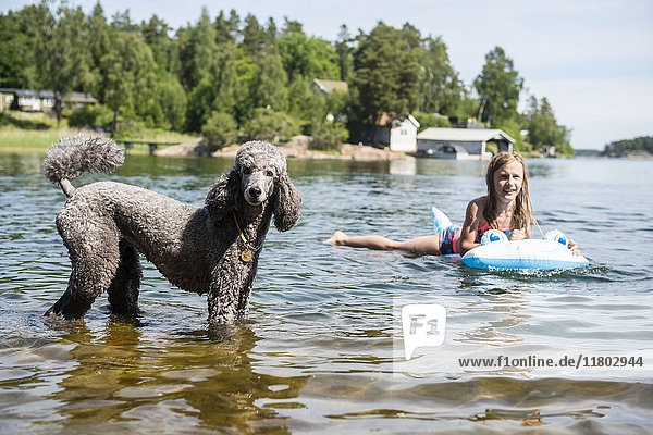 Smiling girl in lake with dog