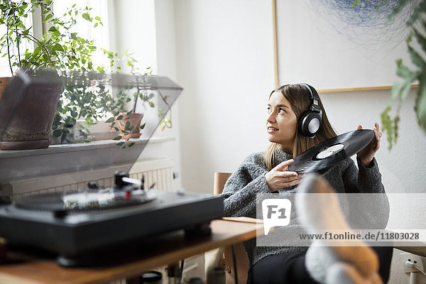 Frau mit Kopfhörern beim Hören von Schallplatten