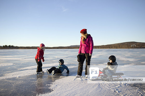 Mutter mit Kindern beim Schlittschuhlaufen auf dem See