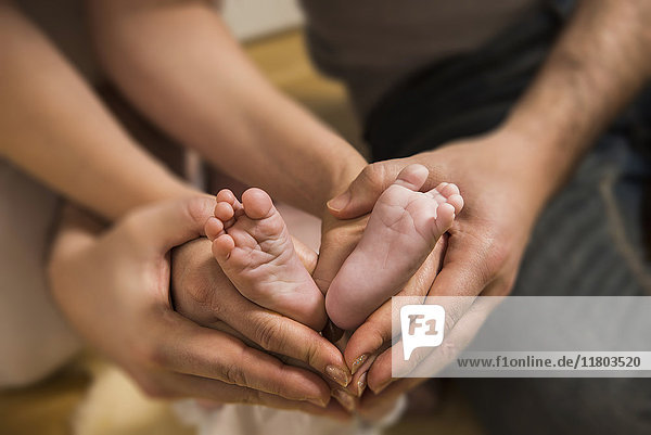 Close - up parents making heart shape symbol around baby boys feet