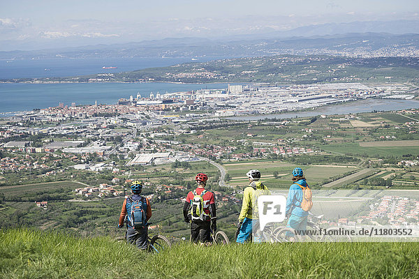 Mountainbiker blicken vom Berg aus auf Stadtbild und Meer