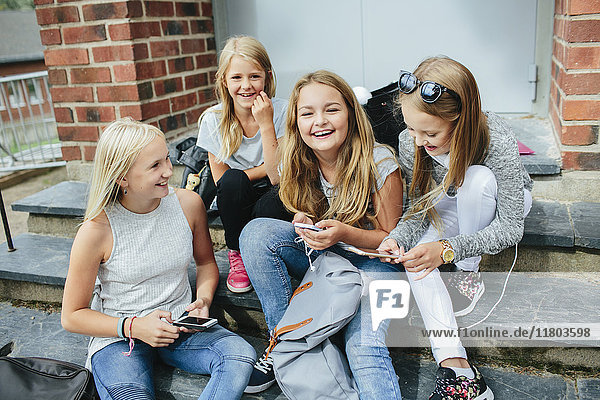 Girls sitting on steps and using cell phones
