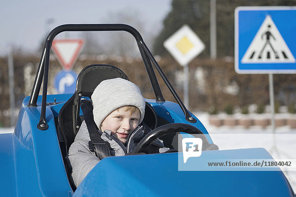 Porträt eines Jungen  der ein elektrisches Spielzeugauto fährt