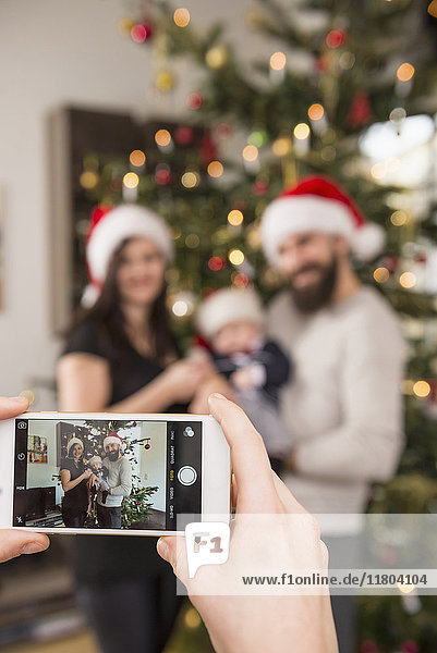 Frau fotografiert Familie mit Telefon