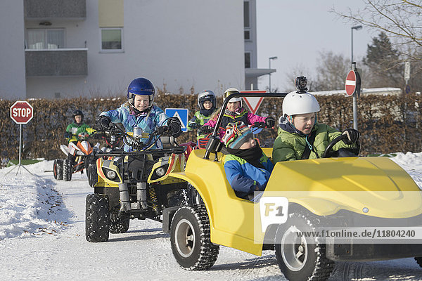Children riding quadbike and toy car on road