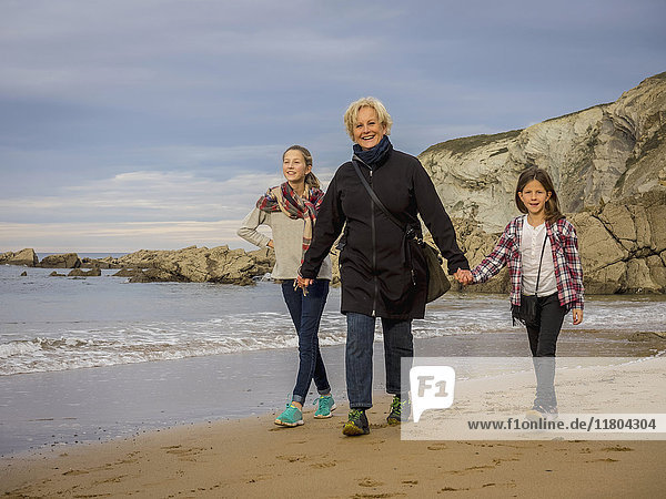 Großmutter geht mit Mädchen am Strand spazieren