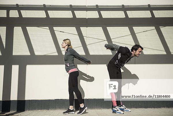 Man and woman in sportswear doing stretching outdoors