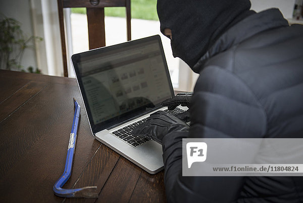 Thief hacker working on laptop and stealing data