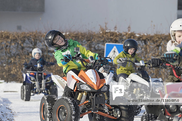 Children riding quadbike on snow covered road