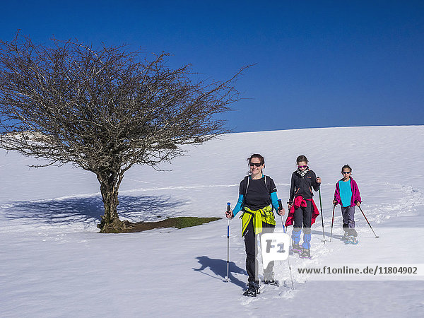 Mutter mit Töchtern beim Wandern auf einer Schneepiste