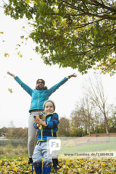 Mother and son enjoying by throwing autumn leaves in the air