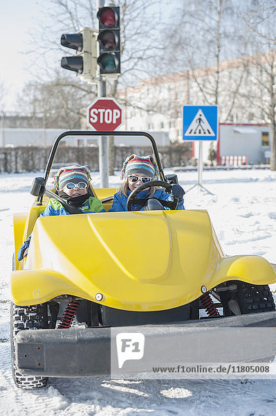 Portrait of boys driving electric toy car on road